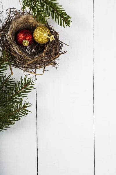 Χριστουγεννιάτικες μπάλες σε μια φωλιά και έλατα κλαδιά. — Φωτογραφία Αρχείου