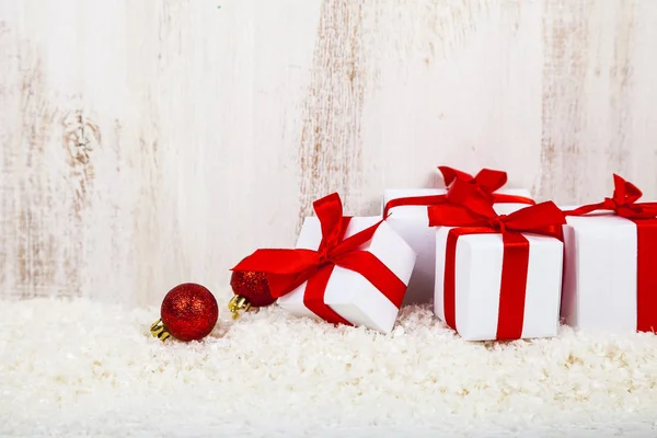 Cadeaux avec des arcs rouges sur la neige — Photo