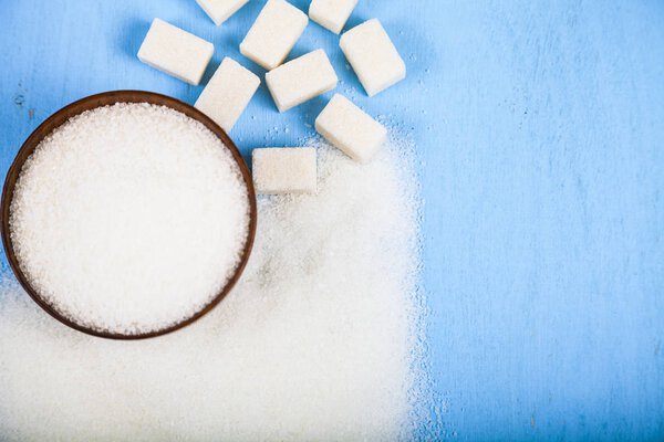 Sugar in a wooden bowl and cubes of sugar 