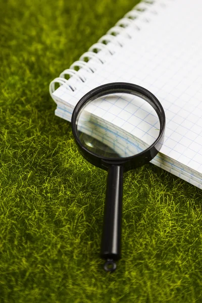 Defter ve Büyüteç çimenlerin üzerinde