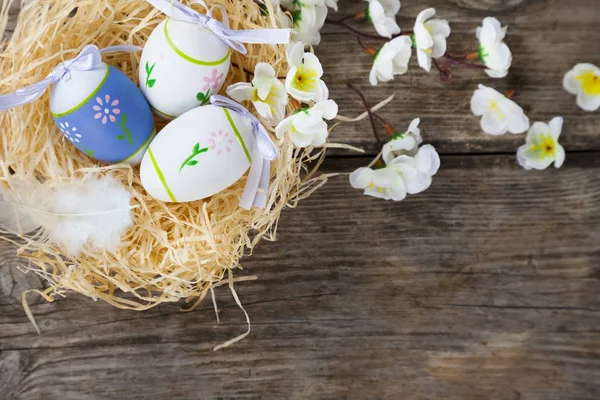 Пасхальні яйця в гнізді і квіти — стокове фото