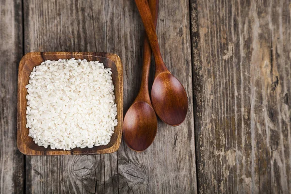 Arroz crudo en un tazón y dos cucharas — Foto de Stock