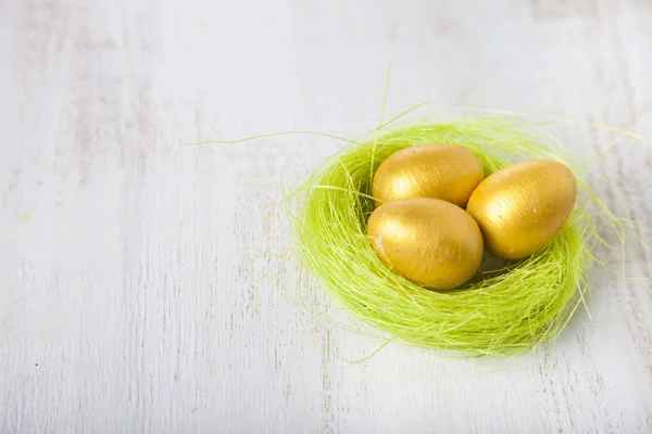 Złote jaja w gnieździe na podłoże drewniane — Zdjęcie stockowe