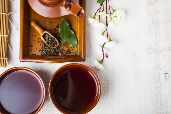 Keramická konvice na čaj, čajové lístky a sakura — Stock fotografie