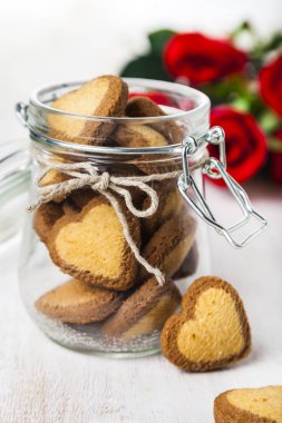 Kalp şeklinde tanımlama bilgilerinde bir cam kavanoz ve kırmızı güller 