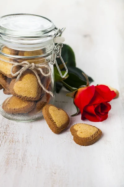 Galletas en forma de corazón en un frasco de vidrio y rosas rojas —  Fotos de Stock