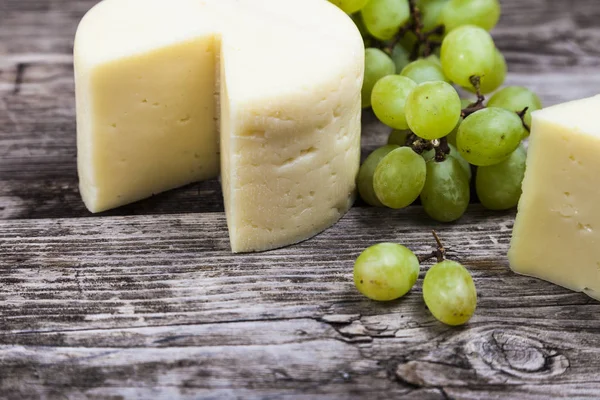 Queijo e uvas em uma velha mesa de madeira — Fotografia de Stock