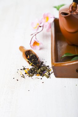 Seramik çaydanlık, çay yaprakları ve sakura