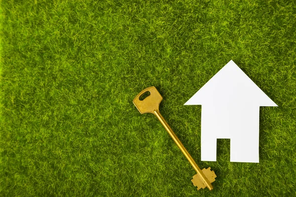 Kartonnen huis en sleutel op gras — Stockfoto