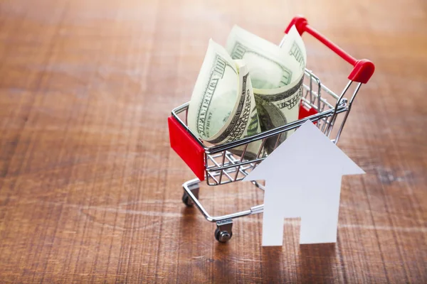 Money in a shop trolley and a house — Stock Photo, Image