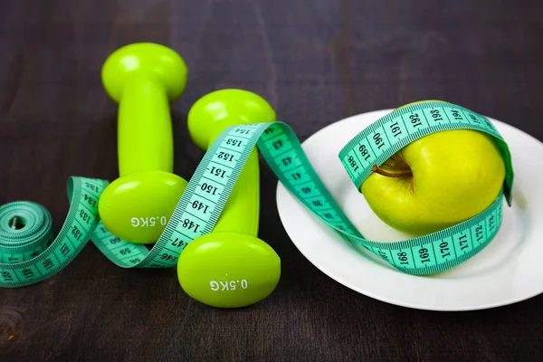 Manzana y cinta métrica en un plato, pesas — Foto de Stock