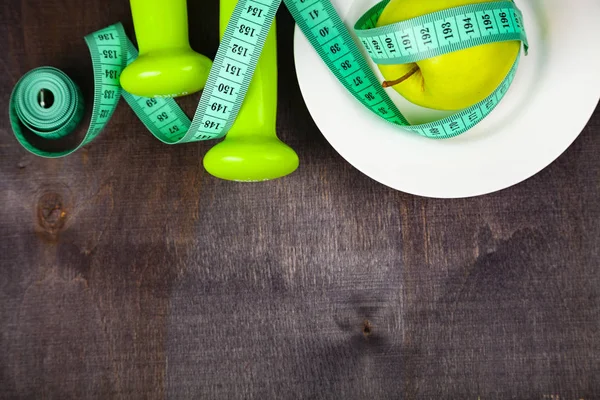 Manzana y cinta métrica en un plato, pesas — Foto de Stock