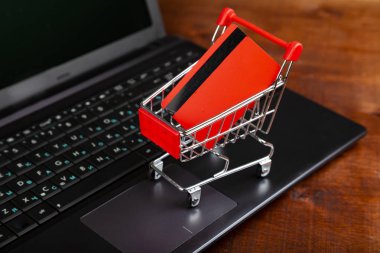 Bir dizüstü bilgisayarda bir alışveriş sepeti içinde kredi kartı