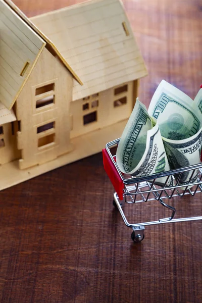 Money in a shop cart and a house — Stock Photo, Image