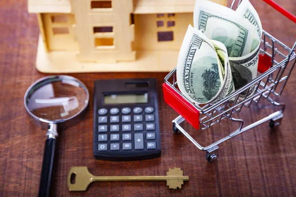 Penger i en butikk, kalkulator, nøkkel og et hus – stockfoto