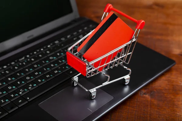 Tarjeta de crédito en un carrito de compras en un ordenador portátil — Foto de Stock