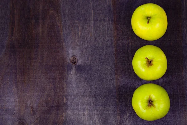 Trzy jabłka na ciemnym tle drewnianych — Zdjęcie stockowe