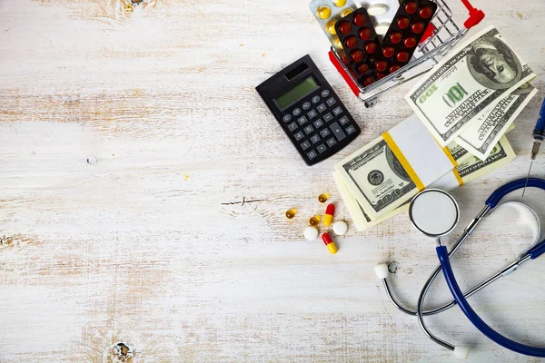Carrinho de compras com pílulas, dinheiro e calculadora — Fotografia de Stock