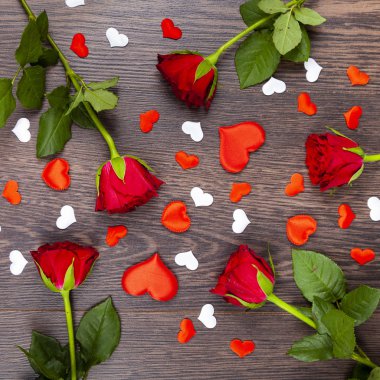 Kırmızı gül ve kalpleri bir ahşap zemin üzerine. 