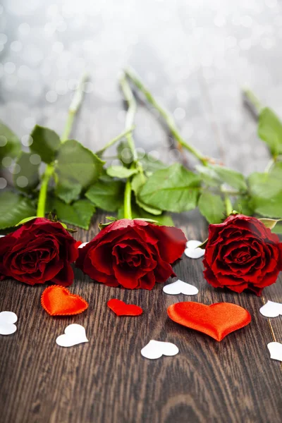 Κόκκινα τριαντάφυλλα και καρδιές σε φόντο ξύλινη. — Φωτογραφία Αρχείου