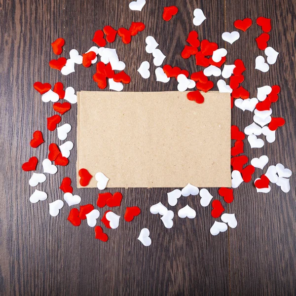 Corações vermelhos e cartão em um fundo de madeira . — Fotografia de Stock