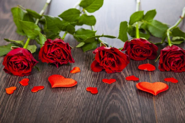 Rode rozen en harten op een houten achtergrond. — Stockfoto