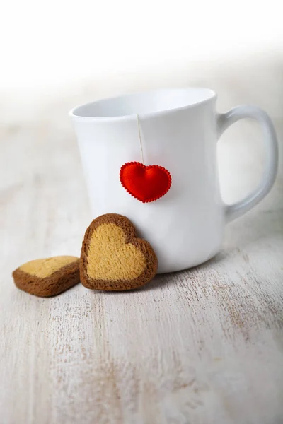 Copo branco com um coração e biscoitos . — Fotografia de Stock