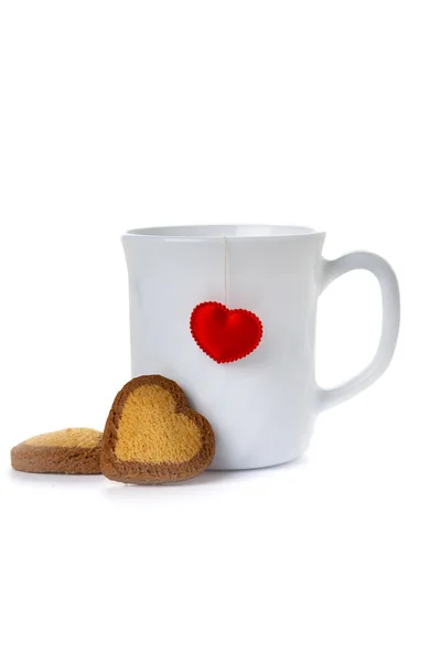 Bílý pohár se srdcem a sušenkami. — Stock fotografie