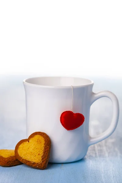 Witte beker met een hart en koekjes. — Stockfoto