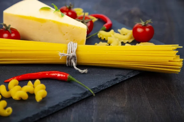 Espaguete, queijo e pimentão em fundo preto . — Fotografia de Stock