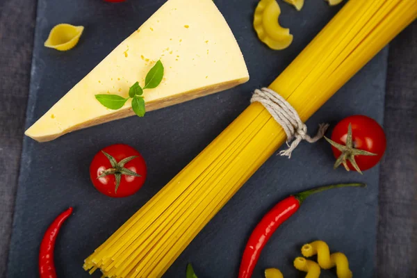 Espaguete, queijo e pimentão em fundo preto . — Fotografia de Stock