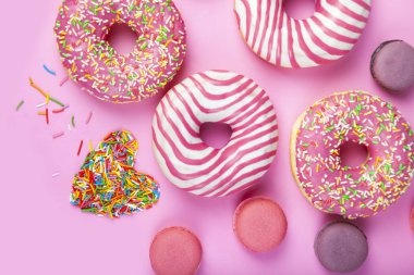 Pembe arka planda çörekler ve makaronlar.