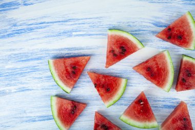 Mavi ahşap bir masada karpuz parçaları.