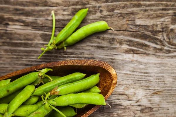 Groene Erwten Een Houten Kom Pea Pods Een Houten Achtergrond — Stockfoto