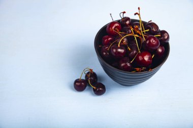 Tahta bir masa üzerinde siyah bir kase olgun tatlı kiraz. Lezzetli meyveler.