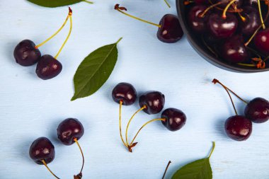 Ahşap bir masa üzerinde siyah bir kapta olgun tatlı kiraz, üst görünümü. Lezzetli meyveler.