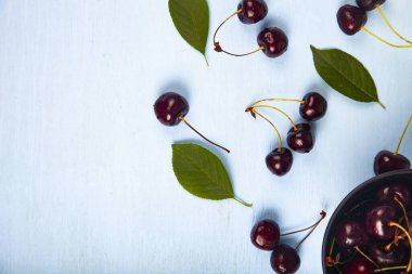 Ahşap bir masa üzerinde siyah bir kapta olgun tatlı kiraz, üst görünümü. Lezzetli meyveler.
