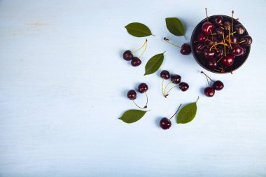 Ahşap bir masa üzerinde siyah bir kapta olgun tatlı kiraz, üst görünümü. Lezzetli meyveler.