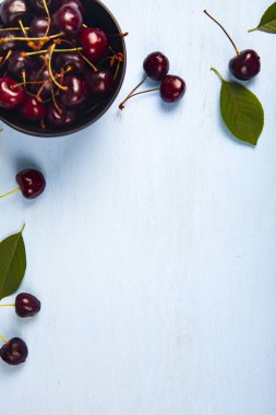 Ahşap bir masa üzerinde siyah bir kapta olgun tatlı kiraz, üst görünümü. Lezzetli meyveler.