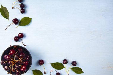 Ahşap bir masa üzerinde siyah bir kapta olgun tatlı kiraz, üst görünümü. Lezzetli meyveler.