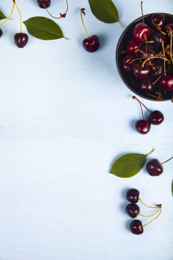 Ahşap bir masa üzerinde siyah bir kapta olgun tatlı kiraz, üst görünümü. Lezzetli meyveler.