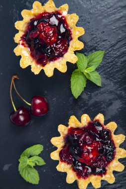 Küçük böğürtlenli kek ve olgun böğürtlenli siyah arkaplan lezzetli tatlı.