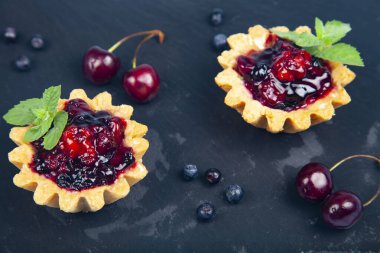 Küçük böğürtlenli kek ve olgun böğürtlenli siyah arkaplan lezzetli tatlı.