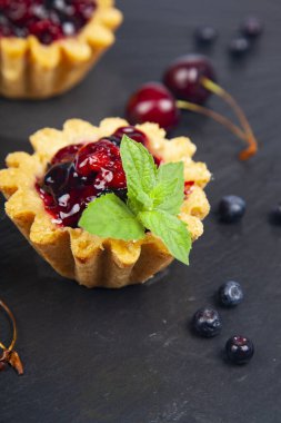 Küçük böğürtlenli kek ve olgun böğürtlenli siyah arkaplan lezzetli tatlı.