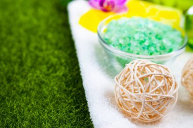 Yeşil çimlerin üzerinde kaplıca aksesuarları ve orkide.