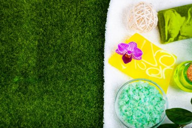 Yeşil çimlerin üzerinde kaplıca aksesuarları ve orkide.