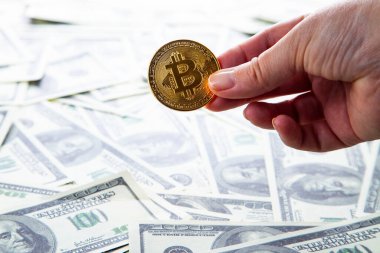 Paranın arka planında bitcoin olan bir el. Dolar ve sanal para.