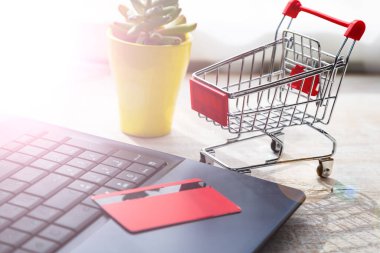 Kredi kartı ve alışveriş arabası olan bir laptop. İnternetten alışveriş.