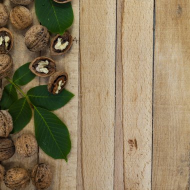 Tahta bir masada ceviz ve yapraklar. Sınır..