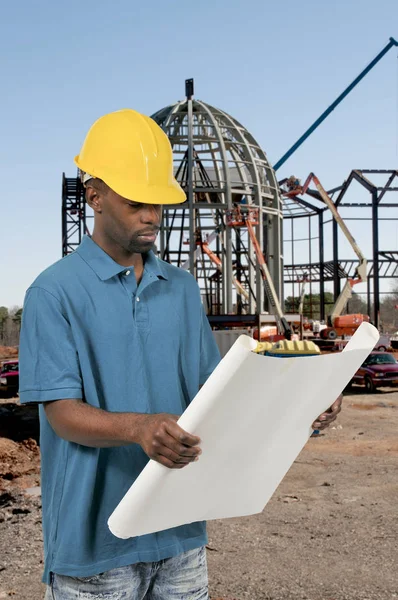 Zwarte bouwvakker met blauwdrukken — Stockfoto
